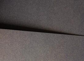 Elegant black paper texture with a shimmering gold sparkle and grainy finish. Luxurious designer photo