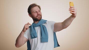 Happy young man traveler blogger taking selfie on smartphone communicating call online stream video