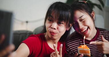 Two Asian siblings pose for a selfie happily and joyfully on a sofa in their living room at home, Capture happy moments together video