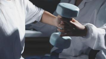 A woman is holding a dumbbell while another person is holding a phone video