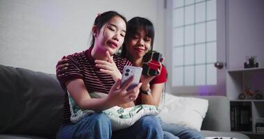 Asian siblings pose for a selfie happily and joyfully on a sofa in their living room at home, Capture happy moments together video