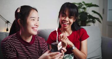 Younger sister gave a small cake to her elder sister and sang a happy birthday song together on the sofa in the cozy room. A happy and warm time video