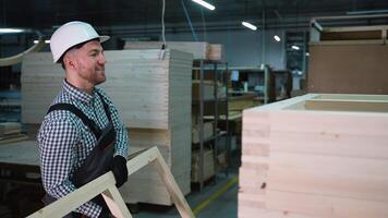 Smiling Carpenter Stacks Wooden Frames in Workshop video