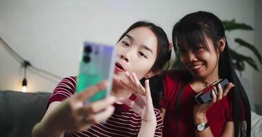 Handheld shot, Two women are having fun taking selfies with smartphone to capture memories in cozy home. video