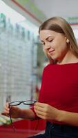 Woman examining eyeglasses. Happy woman choosing glasses at optical store video