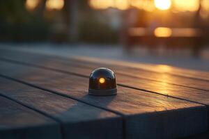 A small black object with a light on it sits on a wooden table photo