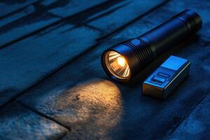 A flashlight and a lighter are on a dark surface photo