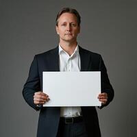 A man in a suit holding a white sign photo