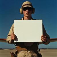 A man in a military uniform holds a blank sign photo
