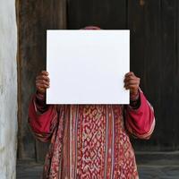A woman is holding a white sign in front of a wooden door photo