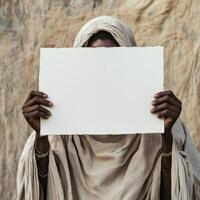 A man is holding a blank piece of paper in front of his face photo