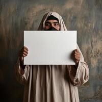 A man wearing a white robe holding a blank piece of paper photo