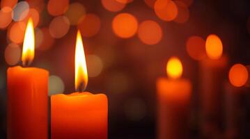 Three orange candles are lit in front of a dark background photo