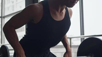 Close-up of pectoral muscles of an Asian athlete performing Romanian deadlifts in gym using barbell. he is concentrating and looking at himself in mirror. video