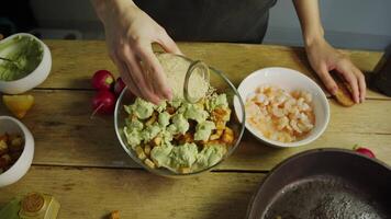 Sesame seeds are poured onto a salad of avocado, seafood, and crackers, in a rustic kitchen. Top view. video