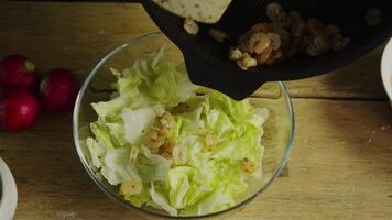 The chef in the restaurant's kitchen cooks and then adds shrimp to the salad in clear glass bowls on a wooden kitchen counter. video