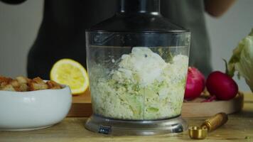 Cook turns on the blender and blends the egg and avocado until they are finely chopped, creating a smooth and homogeneous mixture. video