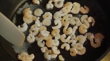 Fresh, thawed shrimp are fried in hot oil in a pan and flipped with a spatula to avoid burning. video