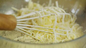 the whisk is in a bowl for mixing cream with grated cheese, pieces of which fall from above. Close up. video