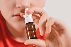 Boy drips nose drops from runny nose. Treatment of colds and allergic rhinitis photo