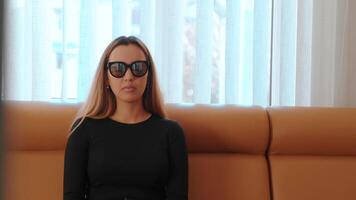 Beautiful girl in glasses sits on a sofa after laser eye correction video