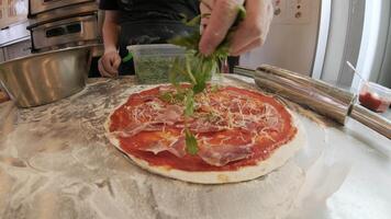 The chef makes the pizza and sprinkle it with herbs video