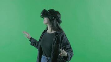 Young woman looks around and wonders how amazing in the VR headset. Virtual reality helmet on the green background. Chroma Key 3 video