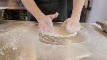 Italian pizza chef forming the dough on a floured surface and rolling out a dough 4 video