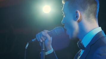 Man singing song in microphone during performance on stage on rock concert. Close up man rock star singer on music concert on colorful light background 9 video