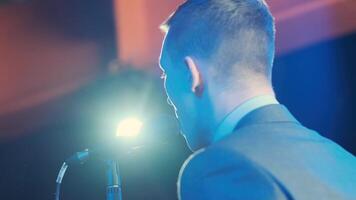 Man singing song in microphone during performance on stage on rock concert. Close up man rock star singer on music concert on colorful light background 13 video
