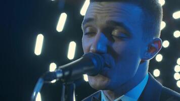 Man singing song in microphone during performance on stage on rock concert. Close up man rock star singer on music concert on colorful light background 4 video