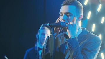 Man singing song in microphone during performance on stage on rock concert. Close up man rock star singer on music concert on colorful light background 6 video