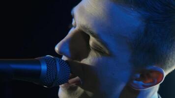 Man singing song in microphone during performance on stage on rock concert. Close up man rock star singer on music concert on colorful light background video