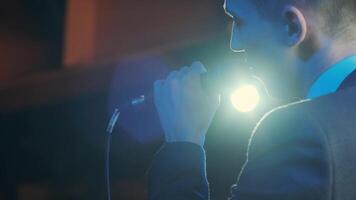 Man singing song in microphone during performance on stage on rock concert. Close up man rock star singer on music concert on colorful light background 10 video