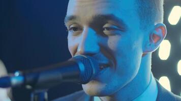 Man singing song in microphone during performance on stage on rock concert. Close up man rock star singer on music concert on colorful light background 7 video
