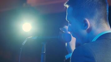Man singing song in microphone during performance on stage on rock concert. Close up man rock star singer on music concert on colorful light background 11 video