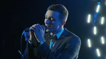Man singing song in microphone during performance on stage on rock concert. Close up man rock star singer on music concert on colorful light background 2 video