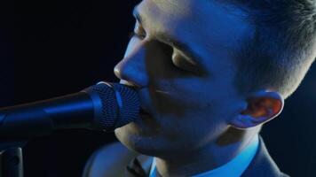 Man singing song in microphone during performance on stage on rock concert. Close up man rock star singer on music concert on colorful light background 3 video