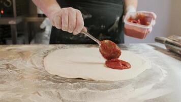 Chef spreading tomato sauce on pizza dough with a metal ladle in pizza restaurant 3 video