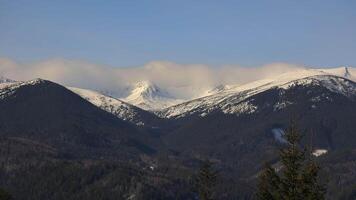 Time lapse of snowy mountain peaks and moving clouds, Time lapse scene showing snow-covered mountain peaks with clouds rolling over video