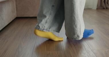 Comfortably dressed in blue jeans and pink socks a person walks in and out of view on a wooden floor showcasing a warm and inviting indoor atmosphere filled with natural light video