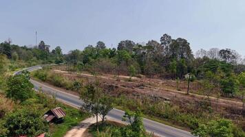 A scenic drone shot of a winding road cutting through lush green hills, surrounded by nature is beauty video