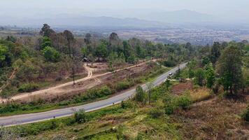 A drone is-eye view of a remote road nestled between hills and forests, ideal for adventure seekers. video