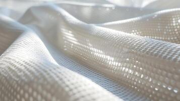 Abstract close-up view of white fabric with a textured, porous pattern, soft folds, and light illuminating the surface.. photo