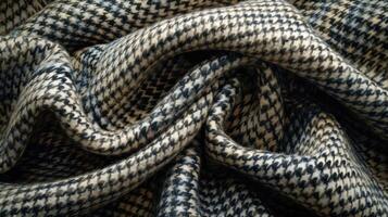 Close-up of a draped, textured fabric with a woven, herringbone pattern in beige and black. photo