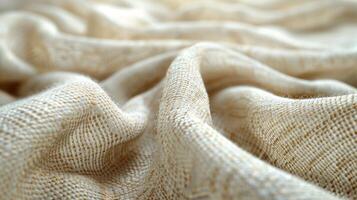 Closeup of a soft, cream-colored, textured fabric with subtle gold threads, wrinkled and draped. photo