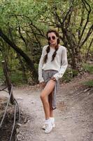 A young girl standing in a park among trees in a hilly area. Hiking in the hills. Active recreation. photo