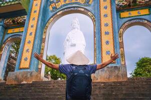 A traveler's man on the background beautiful gate of Linh ung Pagoda and White Lady Buddha at Chua Linh Ung Bai But Temple, Da Nang, Vietnam. photo