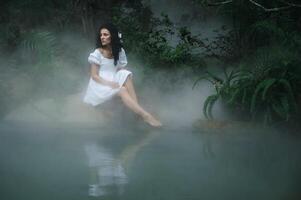 A princess or fairy in a mystical garden by the lake surrounded by trees and fog. Fairyland photo