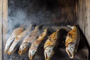 Freshly smoked fish drying in a traditional smoking chamber in a rustic setting photo